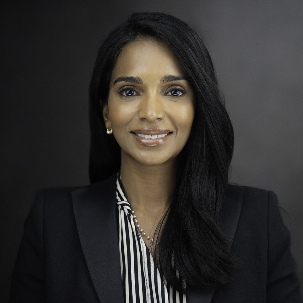 Female executive headshot in black blazer with striped blouse dark studio background NJ
