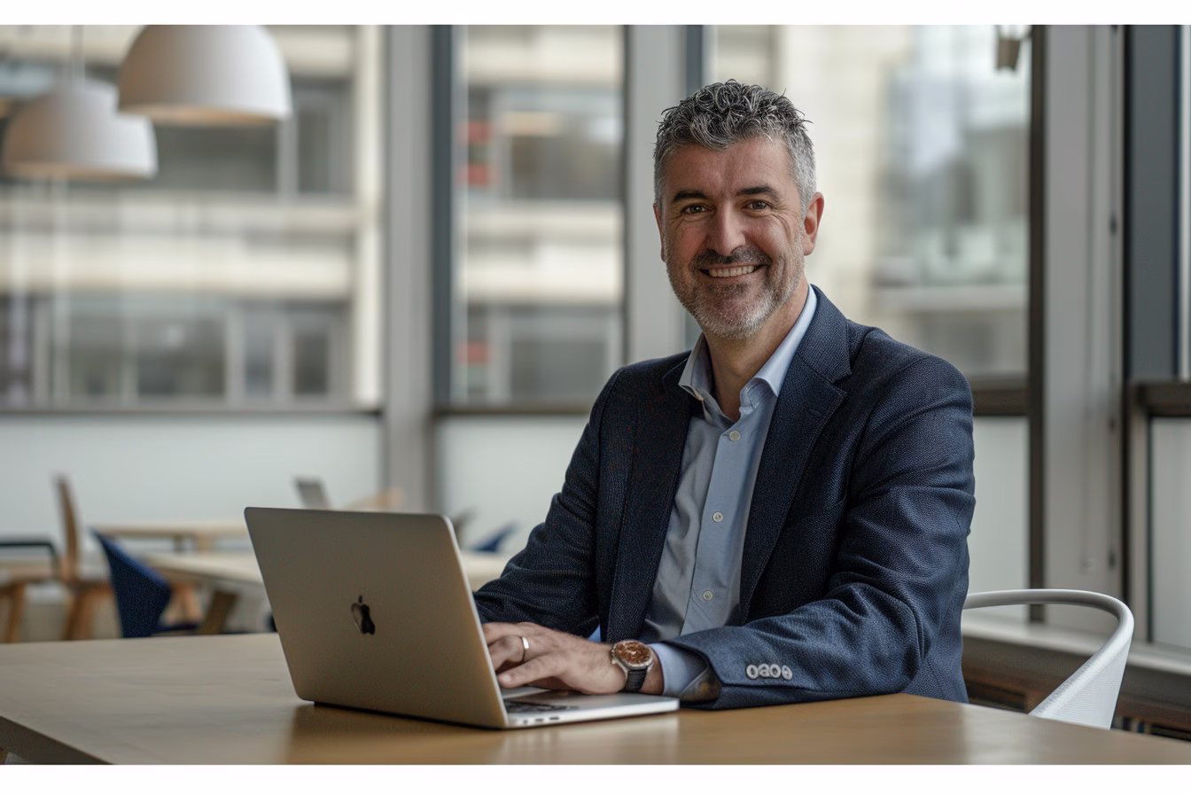 businessman smiling with laptop in office space by alex kaplan headshots