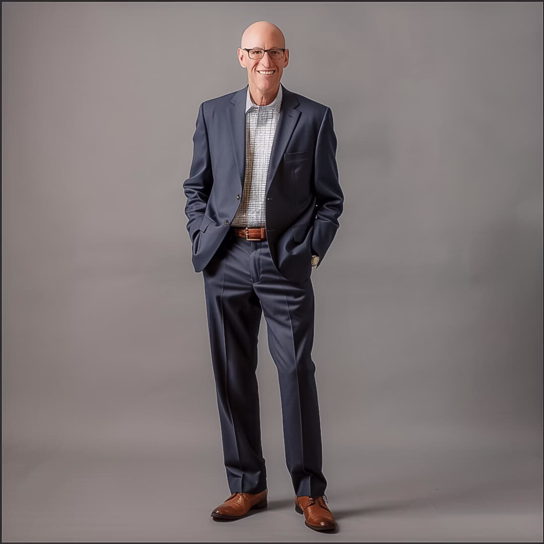Corporate headshot of a man in blue suit and glasses taken in a modern office near Teaneck NJ