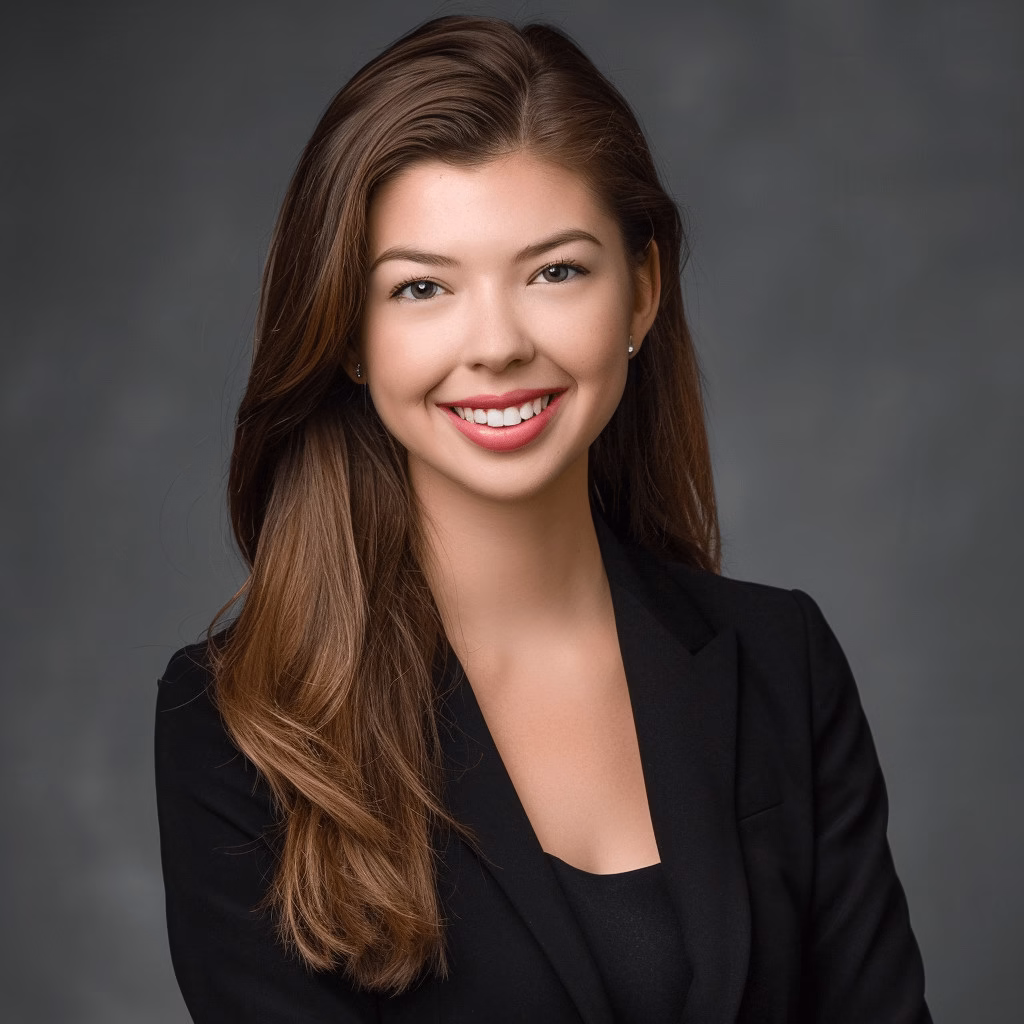 Professional ERAS headshot of a female medical student with long brunette hair, wearing a black blazer and top, smiling confidently against a dark textured background near Hackensack NJ.