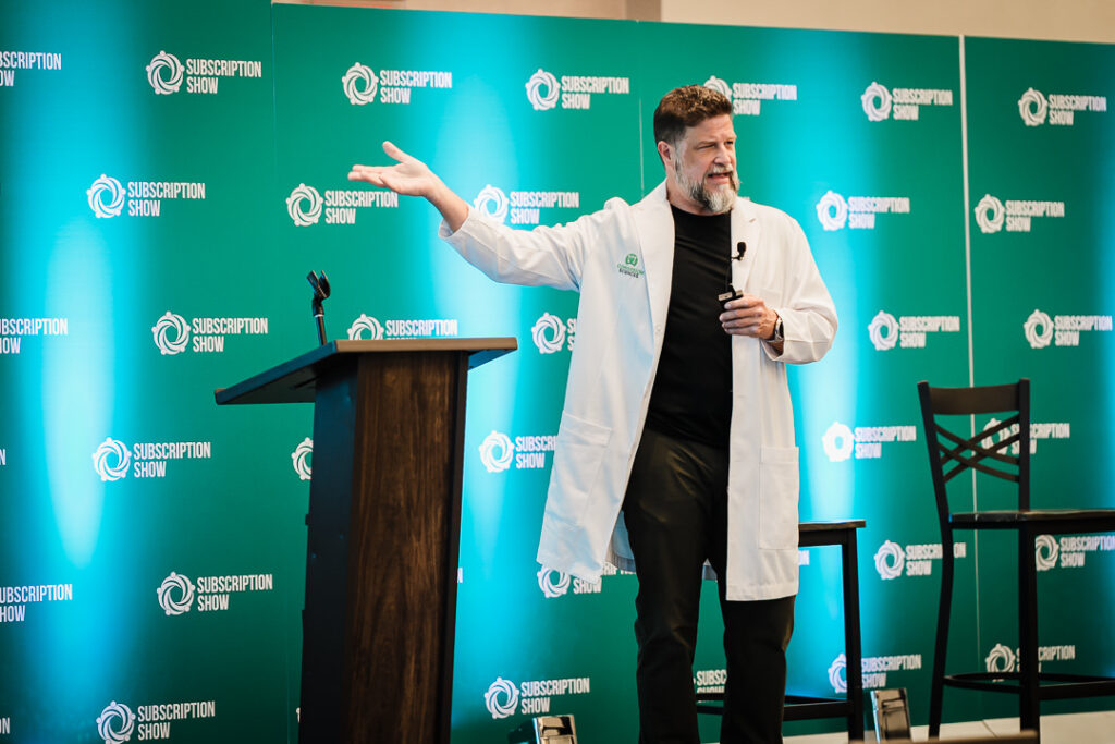 -speaker-presenting-onstage-in-lab-coat-at-business-event-by-alex-kaplan-photography