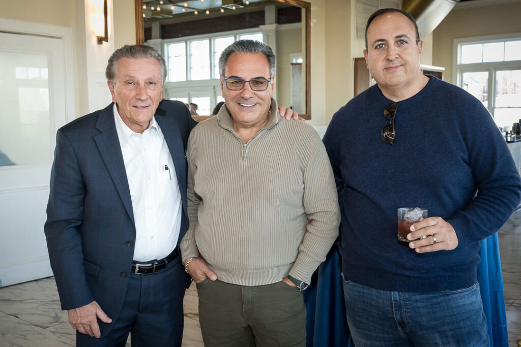 Three men posing together at Tilcon corporate event with bright interior lighting