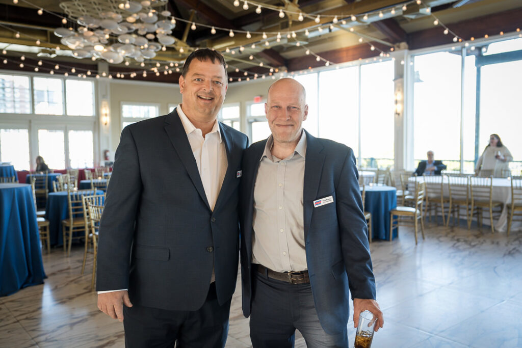 Two executives posing together at Tilcon client appreciation day with string lights overhead