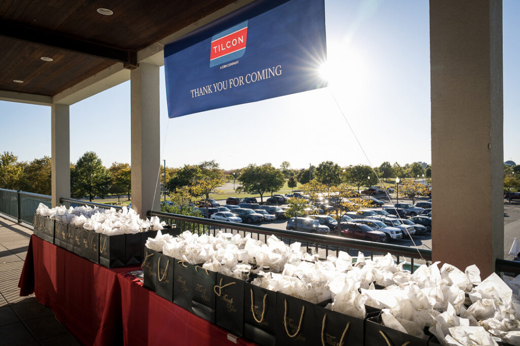 Outdoor terrace setup with Tilcon branded gift bags and white tissue paper against Manhattan skyline backdrop