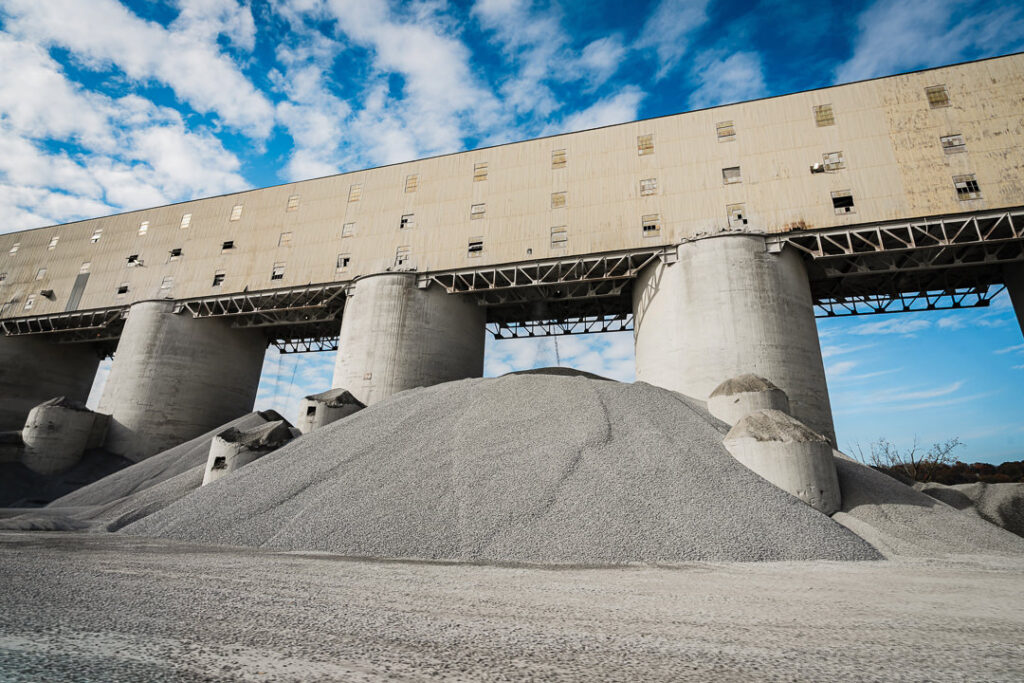 Large aggregate stockpiles beside conveyor system at Clinton Point Quarry in New Hamburg, New York.