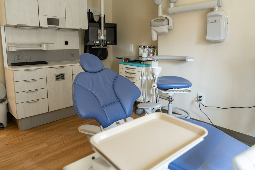 Detailed view of dental treatment room showing blue ergonomic chair, professional instruments, and clean modern design, Alex Kaplan Photography