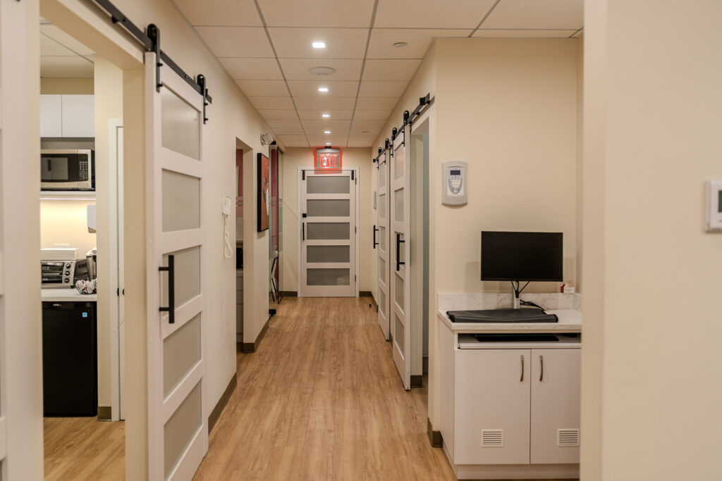 Modern dental office hallway with white sliding barn doors, exit signage, and clean professional design elements, NYC medical office photography by Alex Kaplan