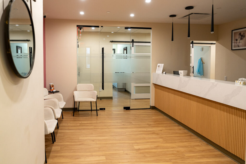 Spacious modern dental reception area with wood-toned desk, white marble countertop, and contemporary seating, Alex Kaplan Photography NYC