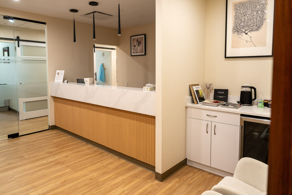 Detail view of Canopy Dental reception desk showing vertical wood paneling and white marble counter with modern amenities, medical branding photography by Alex Kaplan