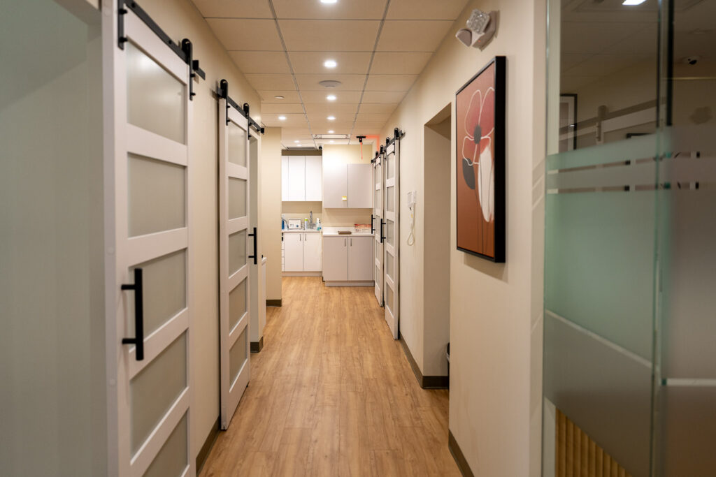 Clean modern dental office hallway with sliding barn doors leading to treatment rooms, professional healthcare branding by Alex Kaplan Photography