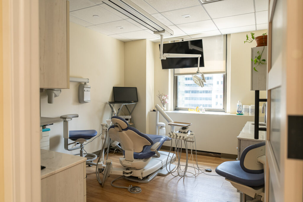 Bright dental treatment room with large windows, blue chair, and natural Manhattan light creating welcoming atmosphere, medical office photography by Alex Kaplan