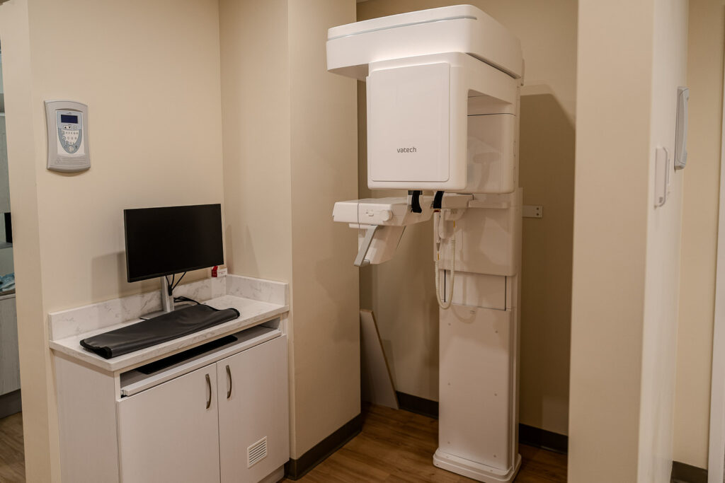 Full view of Vatech imaging station with patient positioning platform and white cabinetry, professional dental office photography NYC