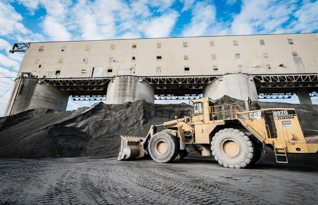 CAT wheel loader positioned beside dark aggregate pile at Clinton Point Quarry industrial work site.