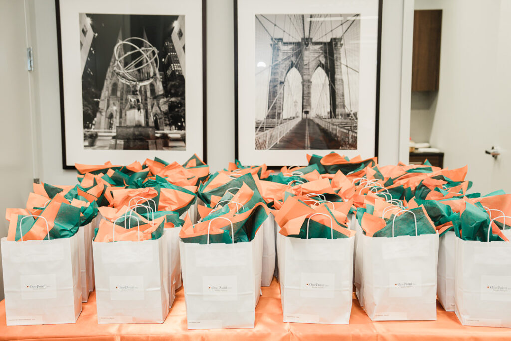 OnePoint branded gift bags with coral and teal tissue paper at launch event