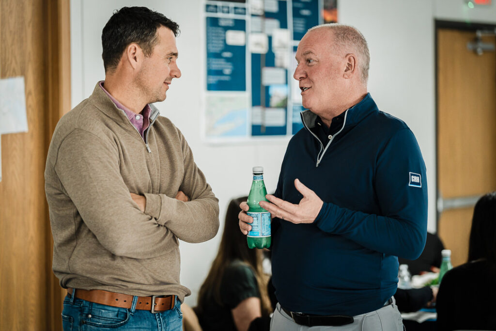 Two Tilcon executives in business casual having informal conversation with project boards visible on wall behind them