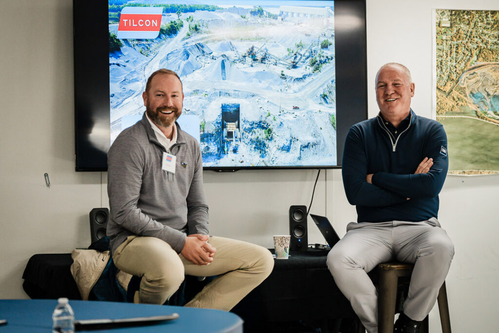 Two Tilcon executives smiling during Q&A session with quarry operations displayed on screen behind them
