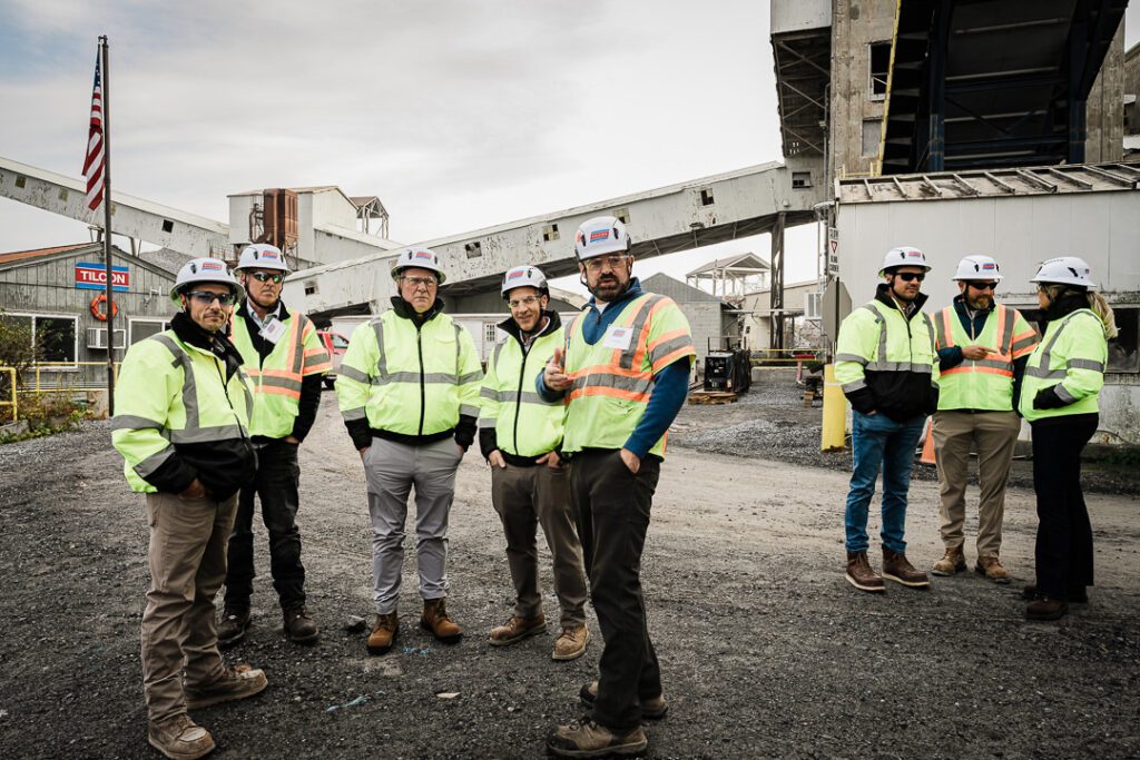 Large group of Tilcon team members in high visibility safety gear posed for photo with American flag at Clinton Point Quarry