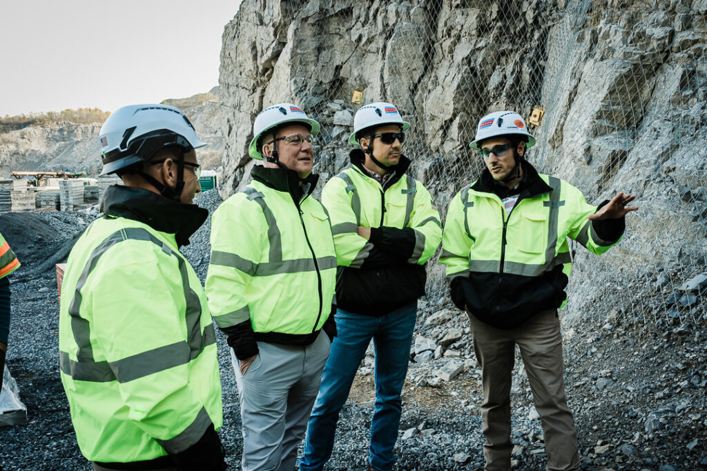 Four Tilcon team members in high visibility safety gear having discussion at Clinton Point Quarry rock face