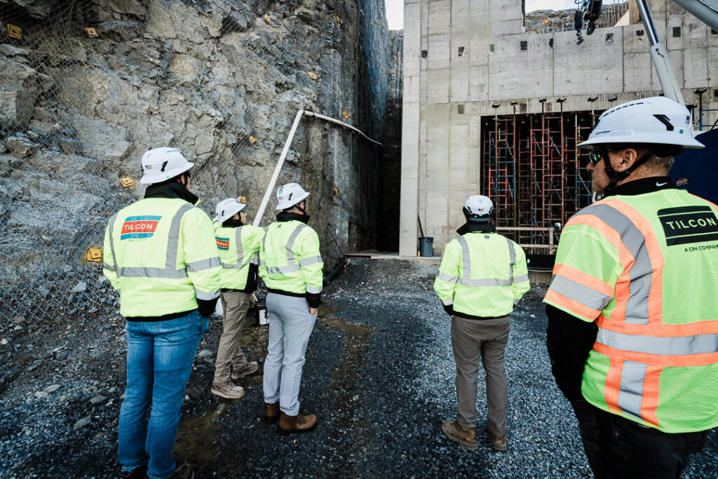 Tilcon leadership team in safety gear at quarry rock face with stability netting visible on cliff wall