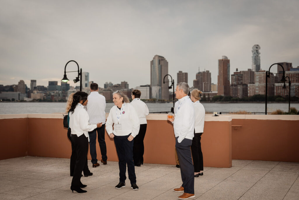 Embecta team members networking on rooftop with NYC skyline by Alex Kaplan Photography