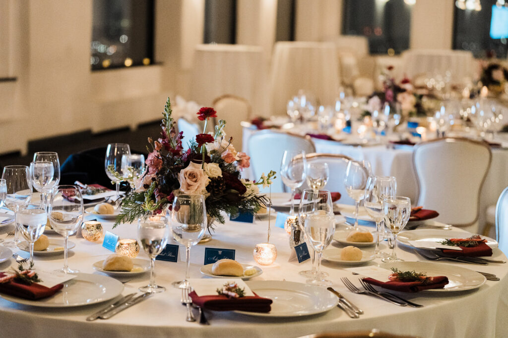 Elegant corporate dinner table setting with burgundy napkins, gold flatware, and floral centerpieces at The High Lawn West Orange NJ photographed by Alex Kaplan