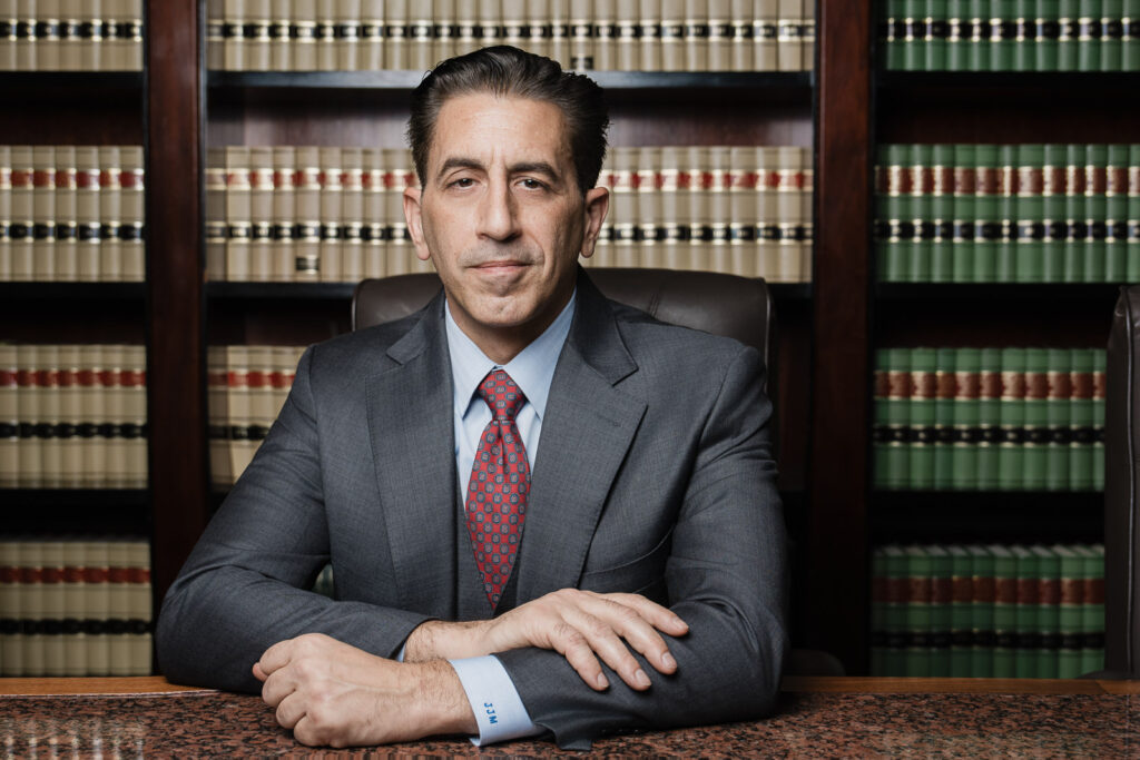 Professional NJ attorney headshot at desk with law library background by Alex Kaplan Photography Bergen County