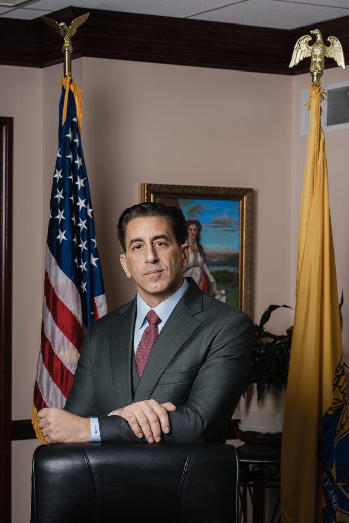 New Jersey law firm headshot of Maggiano attorney in office with American flag and state flag by Alex Kaplan Photography