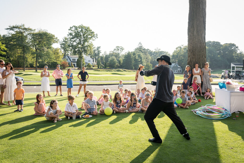 Juggler performing on lawn at The Apawamis Club with American flag backdrop photographed by Alex Kaplan