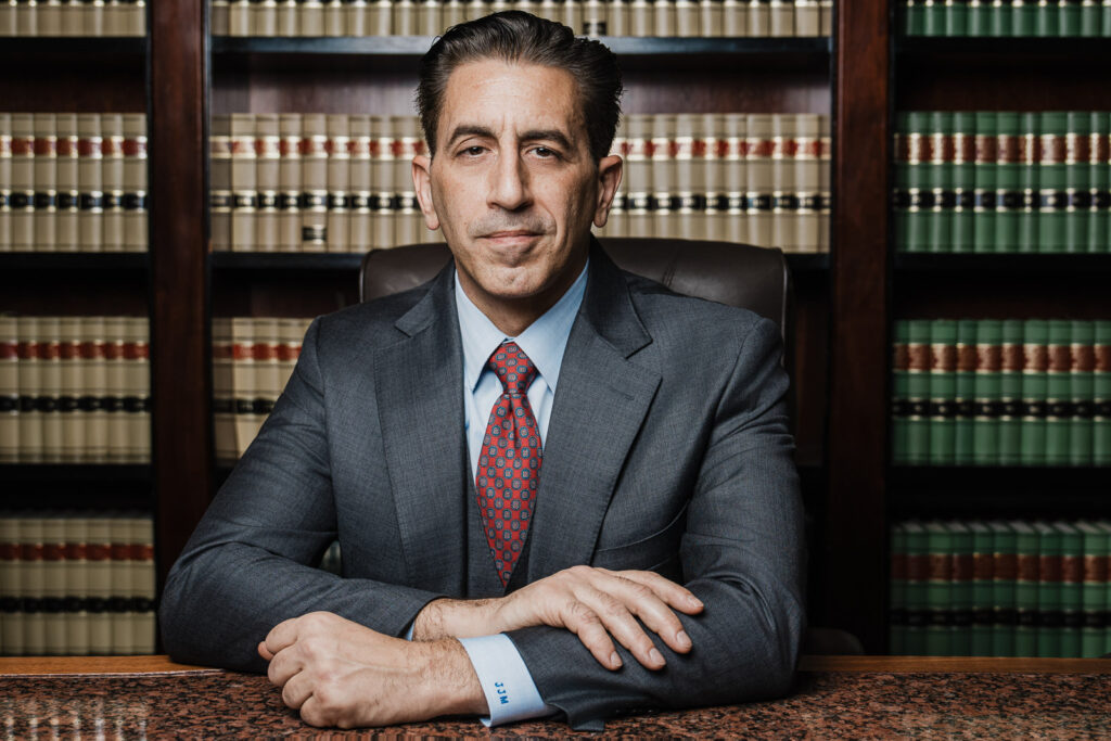 Attorney professional headshot at desk with law library background Bergen County New Jersey