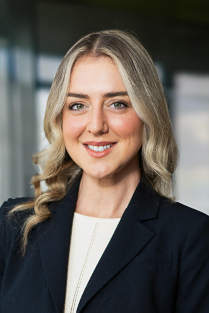 Executive headshot with modern glass architecture in soft focus creating depth and professionalism