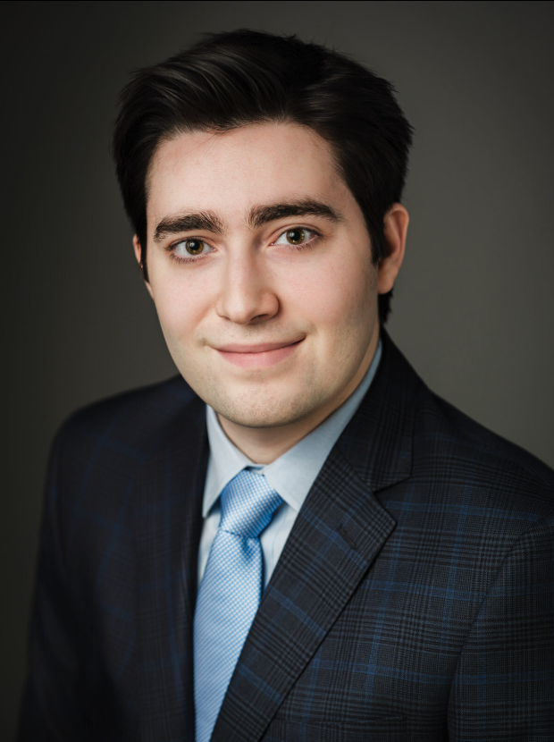 Graduate school application headshot of young man in navy suit and tie on gray studio background — New Milford NJ
