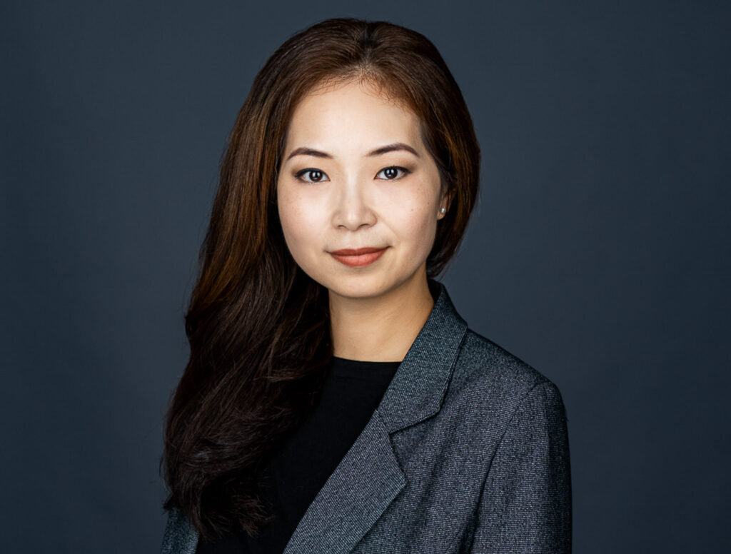 Professional businesswoman in black blazer with natural smile and approachable demeanor in corporate headshot