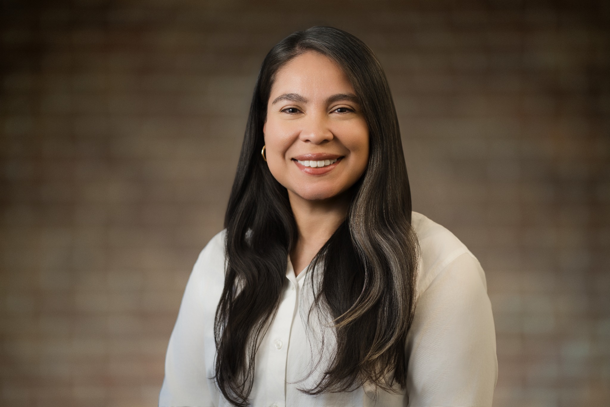 Professional LinkedIn headshot of a woman with a natural smile in a white blouse on a soft neutral background, photographed in Northern New Jersey by Alex Kaplan Photo.