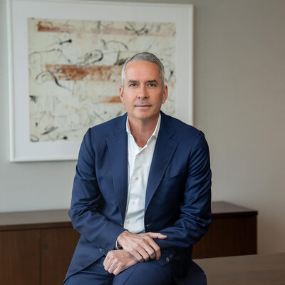 Man in navy suit open collar seated for professional headshot session in New Jersey