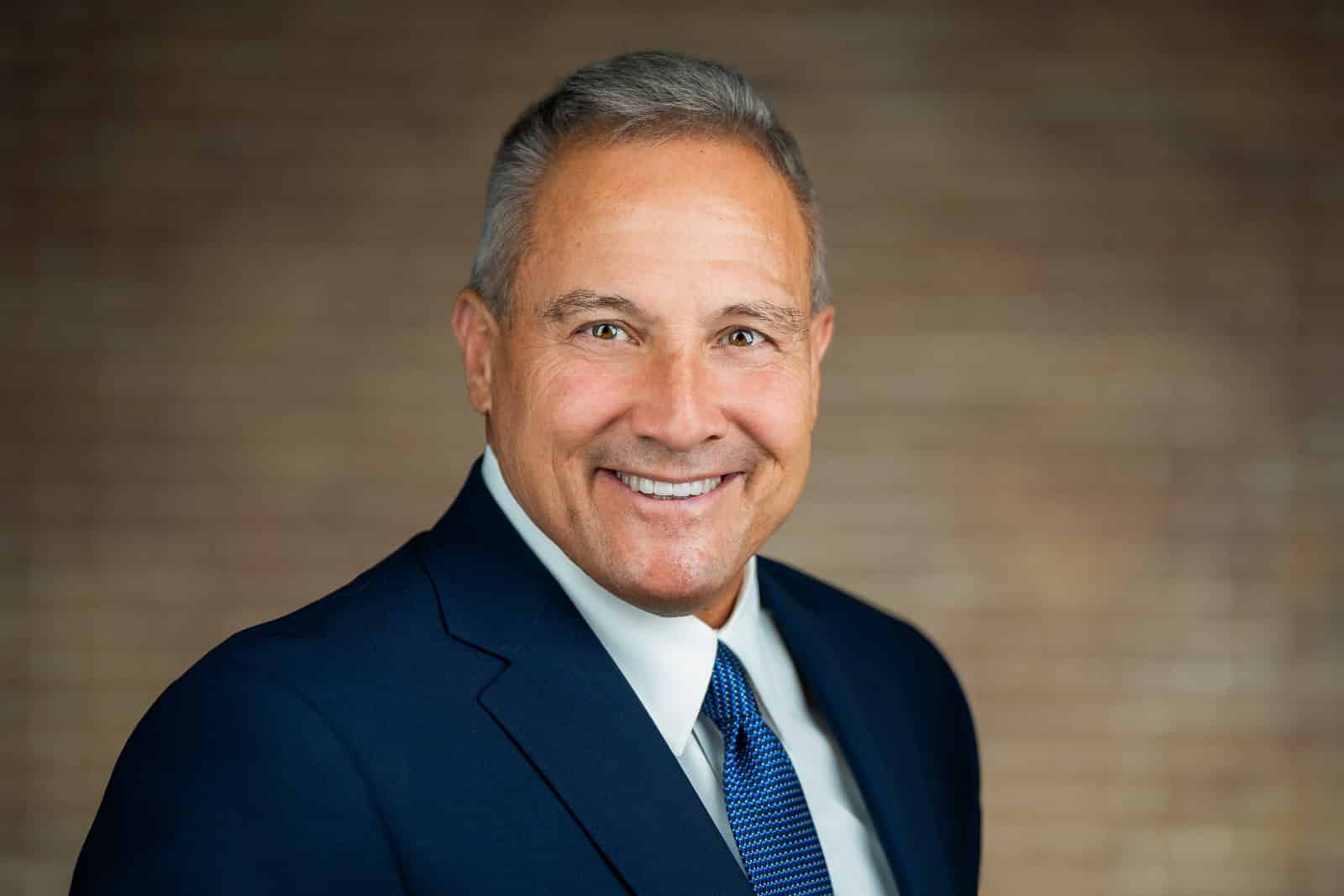 Corporate team headshot of smiling man in navy suit and blue tie NJ firm
