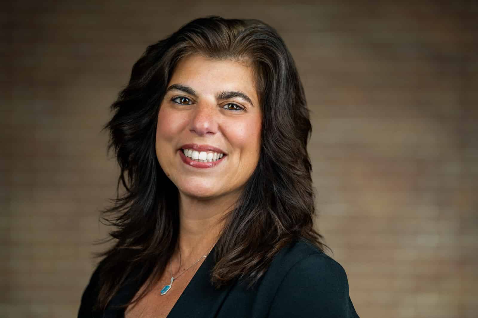 Corporate team headshot of woman in black blazer with warm smile NJ financial firm