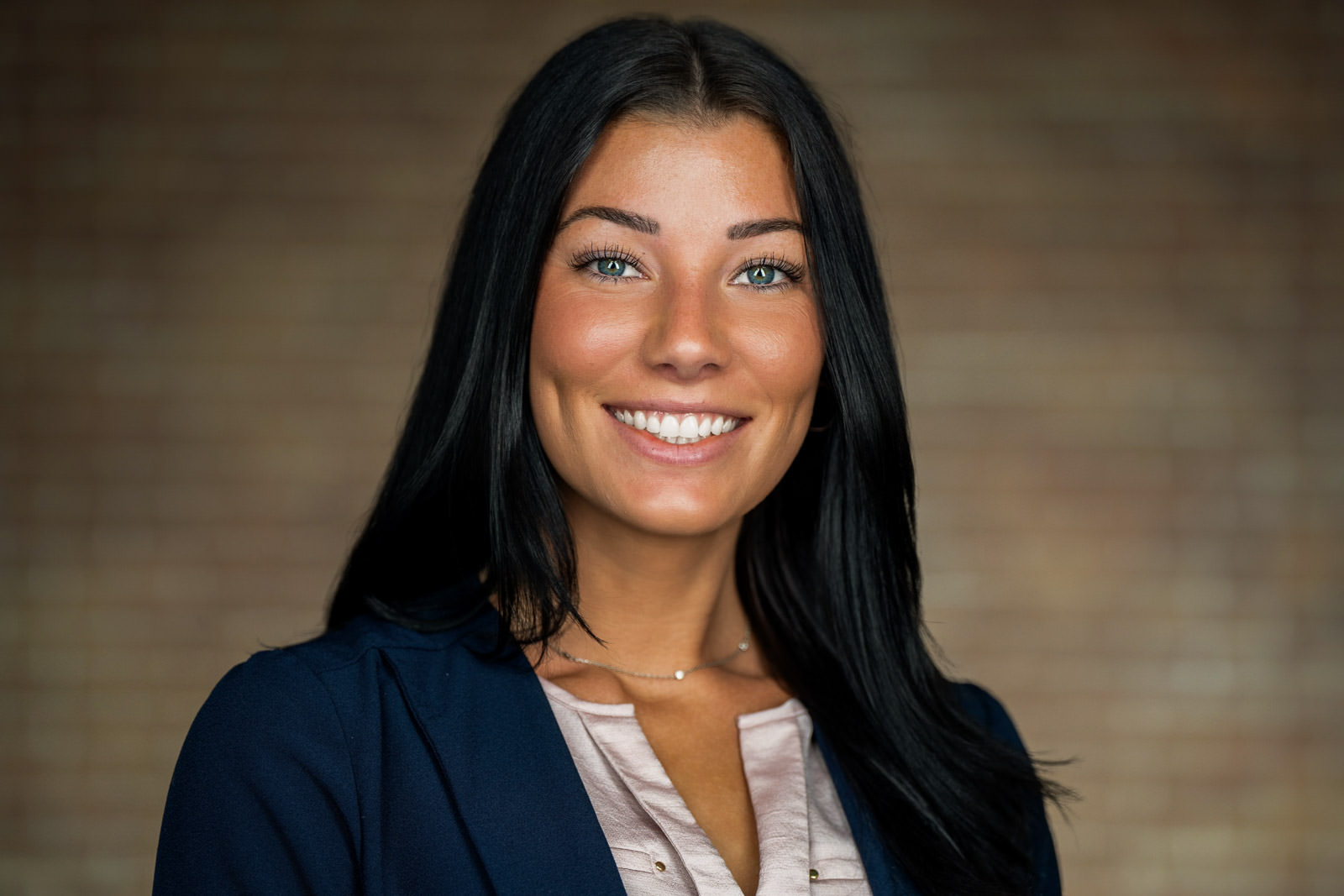 Corporate team headshot of woman in navy blazer warm wood background Parsippany NJ