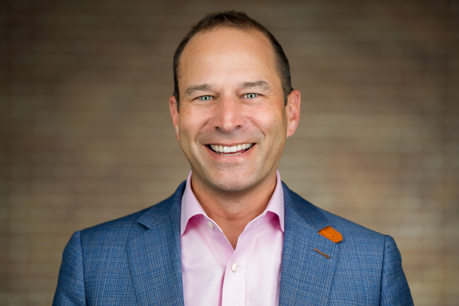 On-location corporate headshot of man in blue blazer pink shirt warm wood background NJ