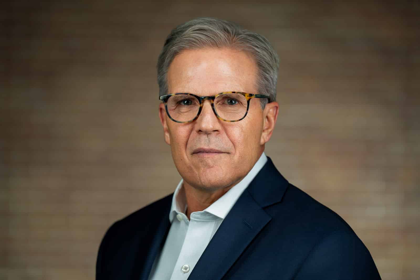 Corporate headshot of senior man with tortoiseshell glasses navy blazer NJ financial firm
