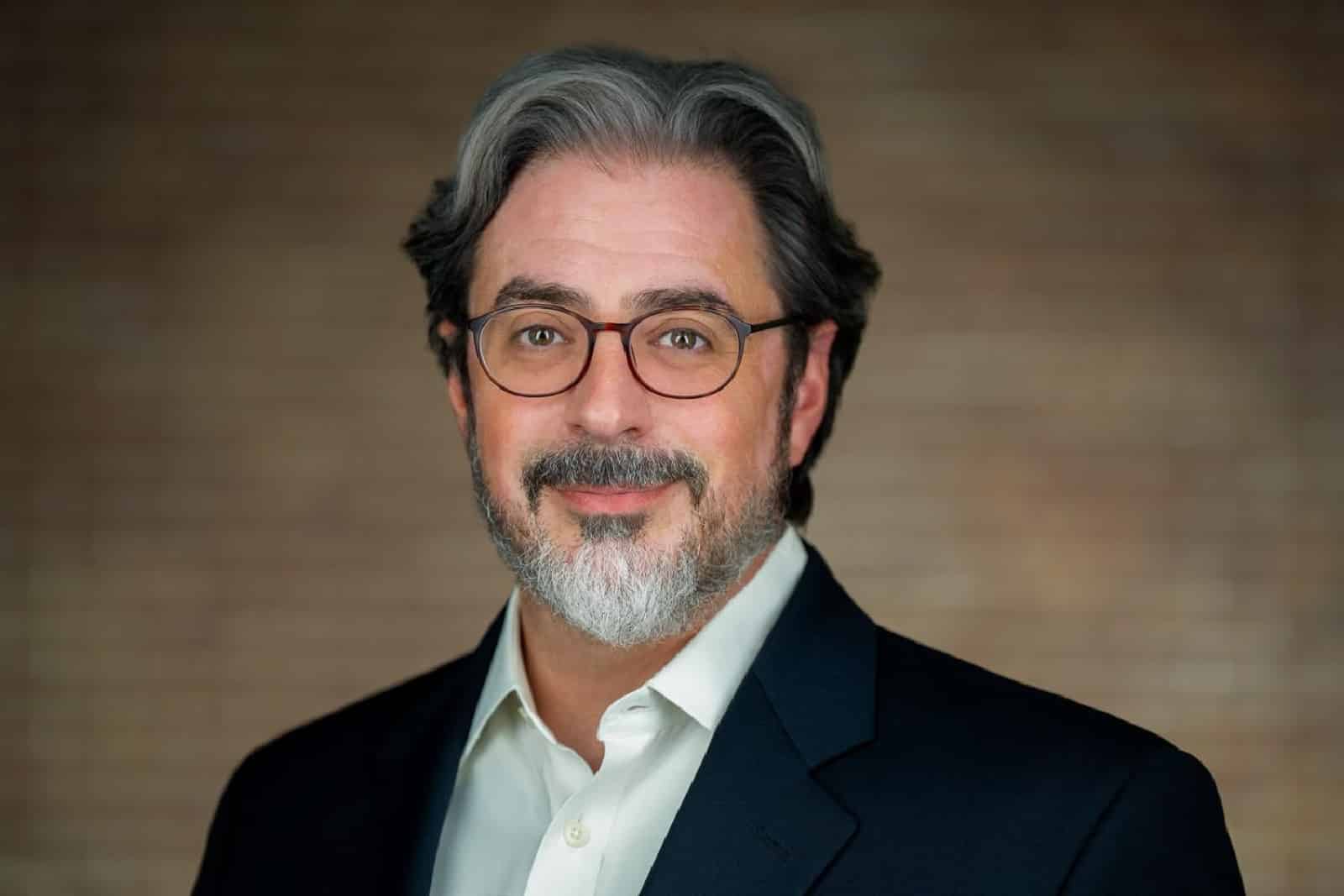 Corporate team headshot of woman in navy blazer warm wood background Parsippany NJ