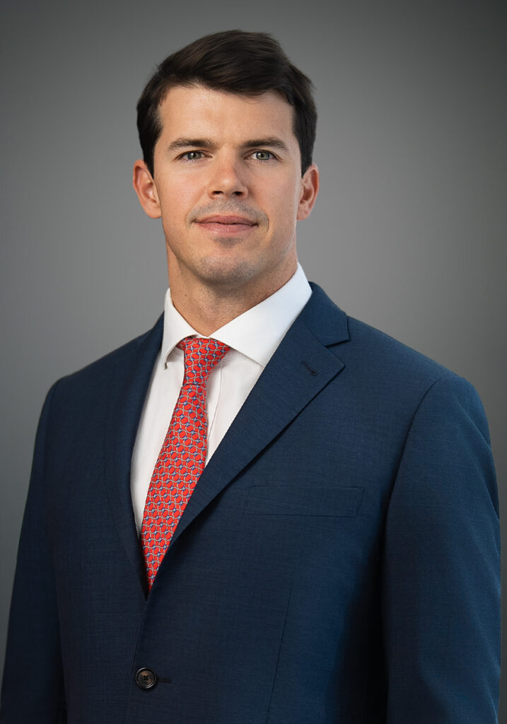 Confident executive headshot of Conor MacLaverty in a navy suit