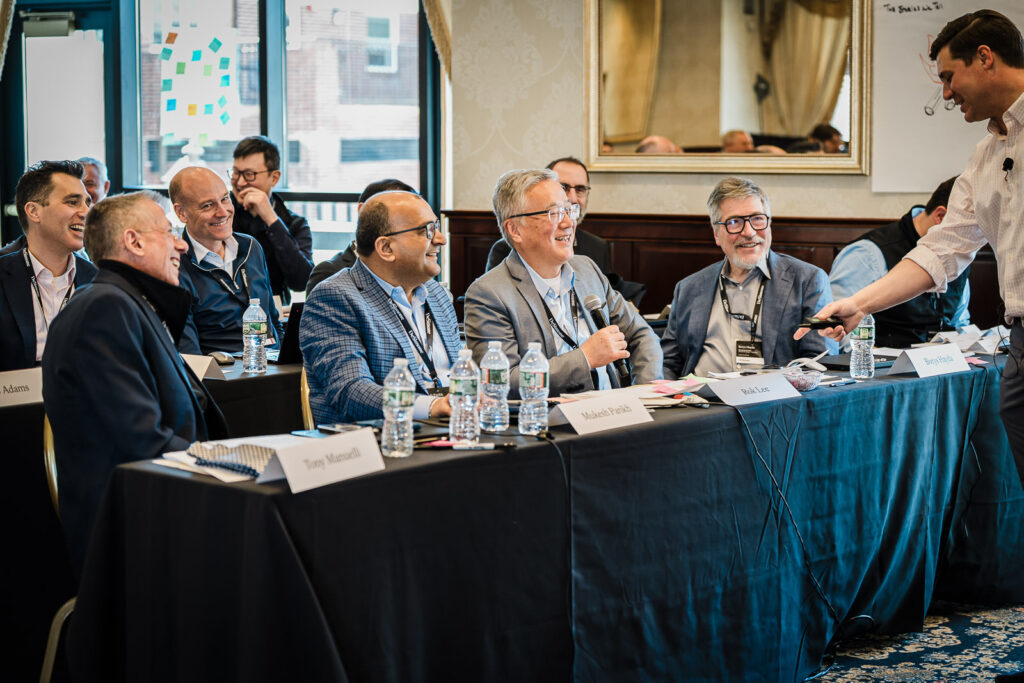 Row of corporate executives sharing a laugh during a panel session at a New Jersey business retreat