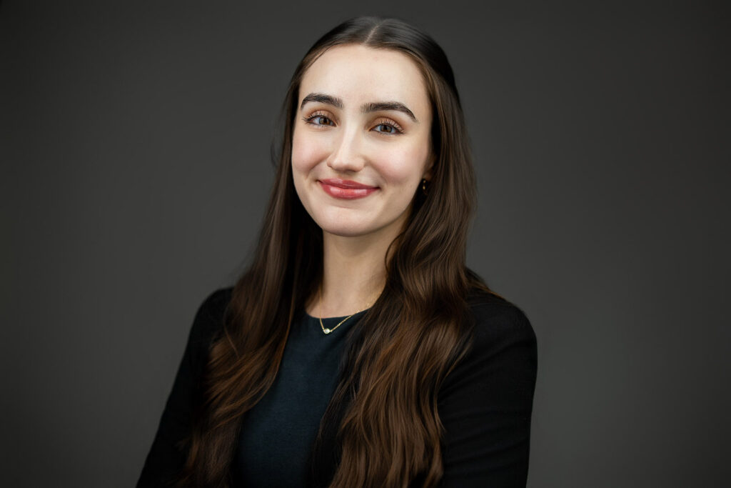 Professional woman in a black blazer smiling softly during a corporate headshot session in New Jersey