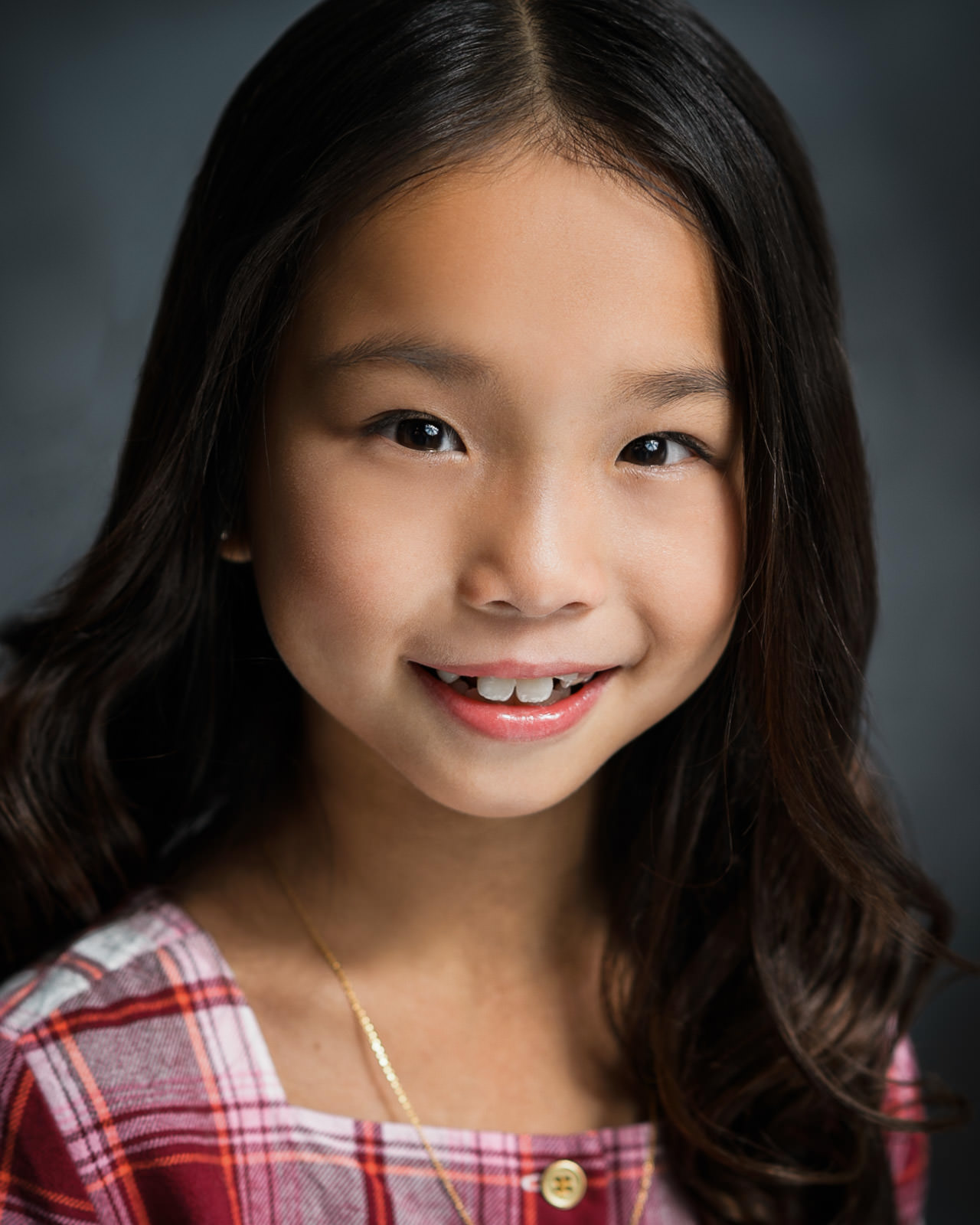 Young child actor smiling naturally during a professional headshot session in NJ with soft studio lighting