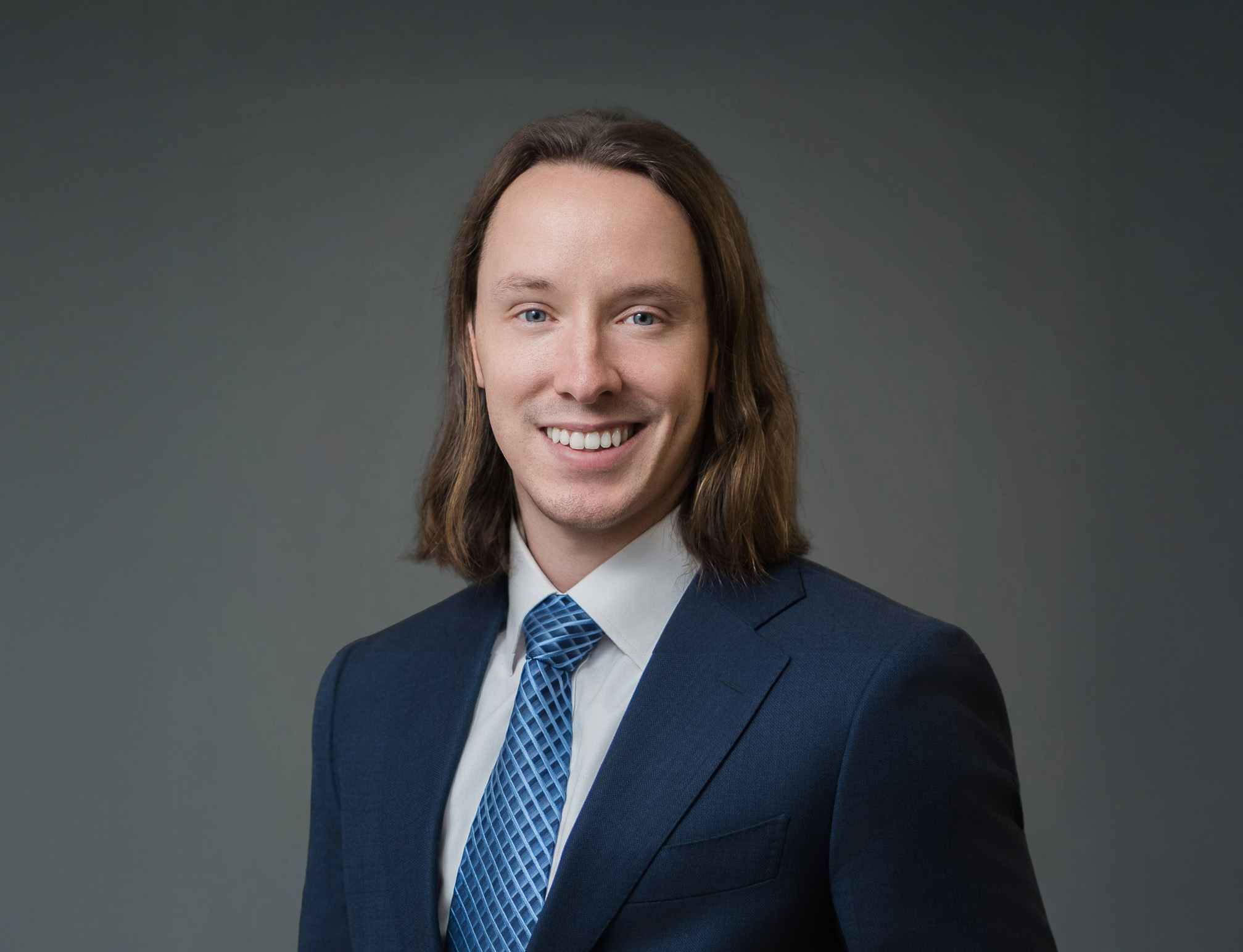 Corporate headshot of a professional man with long hair wearing a navy suit Northern New Jersey studio