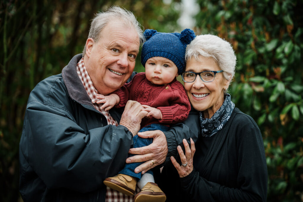 Grandparents holding baby grandson during multi-generational family portrait session at Knight Park in Collingswood New Jersey