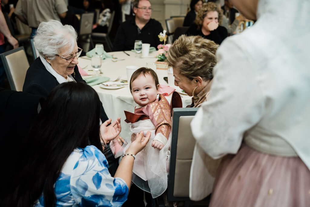 Grandmothers and family members gathered around baby in traditional Korean outfit at a first birthday party in Northern New Jersey