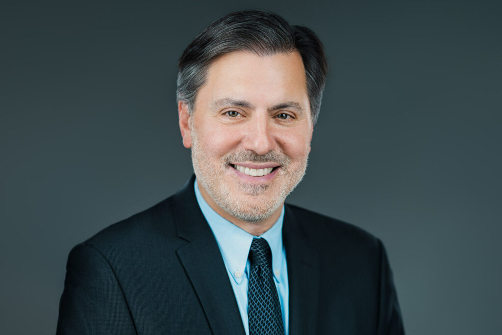Barry smiling in professional actor headshot wearing dark blazer and tie in New Jersey studio