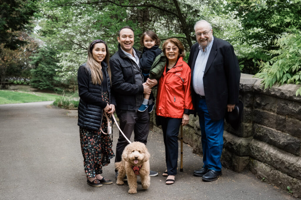 Family photos with grandparents parents toddler and dog laughing on wooded path Northern New Jersey