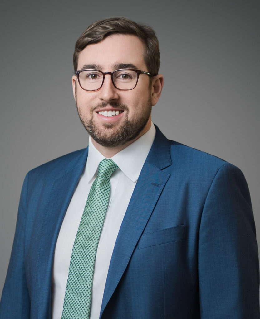 Man in glasses and blue suit smiling in a professional corporate headshot